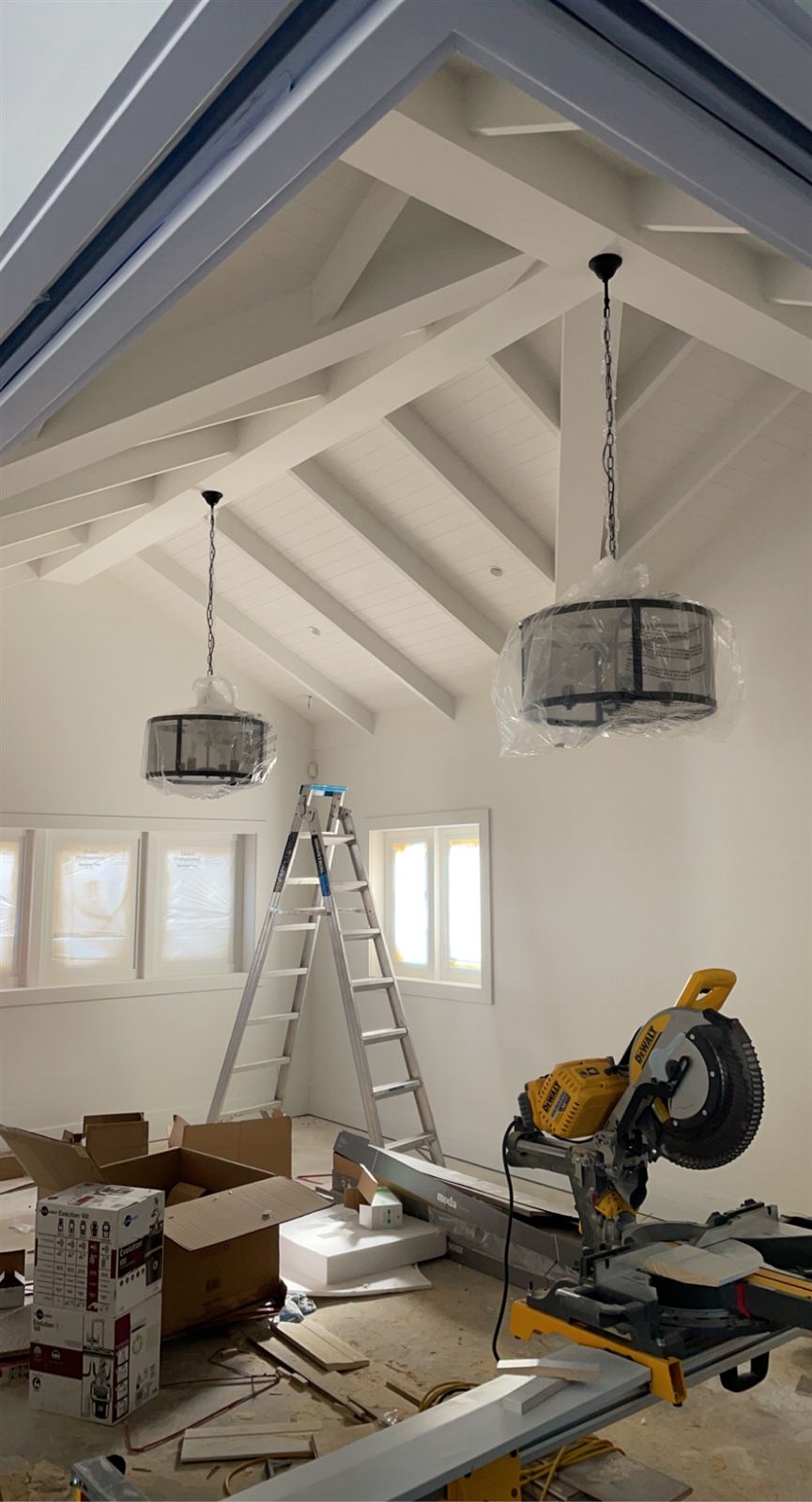 Painted vaulted ceiling with exposed beams and pendant lights being installed